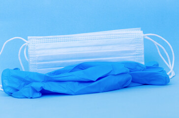 Blue disposable medical grade gloves and face masks above light blue backround. Close up 3d image