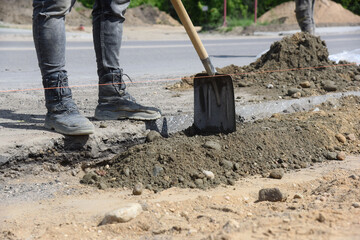 Workers with shovels sprinkle sand along the road, highway construction.