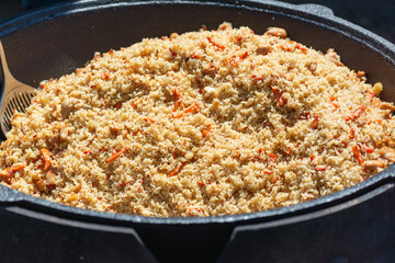 Cooking pilaf in a large pot (cauldron) outside.