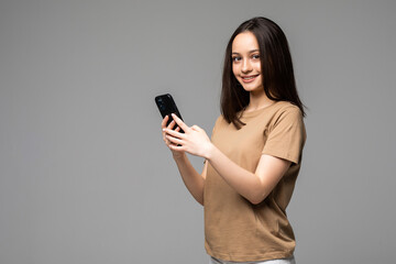 Fototapeta premium Portrait of smiling casual woman holding smartphone over white background