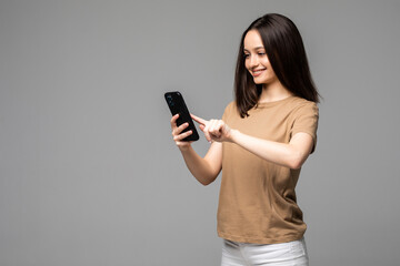 Fototapeta premium Young attractive european student scrolling news feed in her smartphone with concentrated expression, isolated over white background. Girl watches live stream through some app