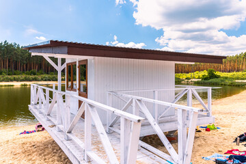 White, wooden lifeguard booth situated on sand beach next to the lake on a beautiful, sunny day