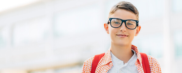 Portrait of a cute boy in glasses who is going to school with his school backpack, Student boy on...