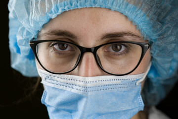 Portrait of a young female doctor in a white coat and mask. Smiling at the camera