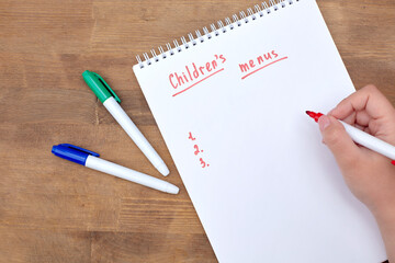 A to-do list in a spiral notebook on a wooden table. An empty space for the text. In the girl's...