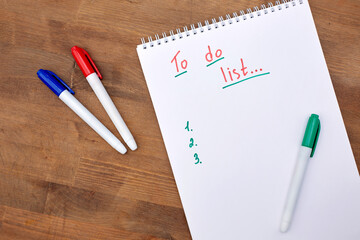 A to-do list in a spiral notebook on a wooden background. An empty space for the text. Written on a sheet, to do list