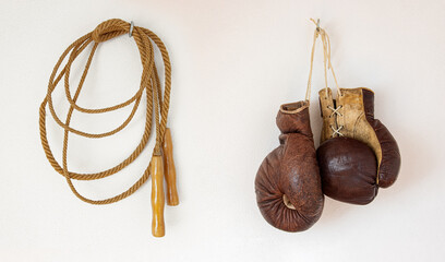 The Old boxing gloves with skipping rope hanging on a white wall