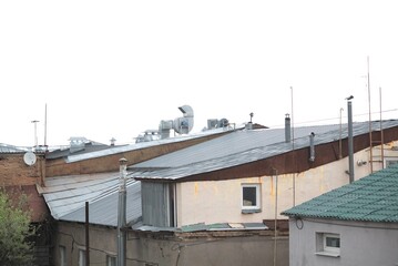 The roof of an old house against the sky with ventilation pipes and attics. Chimneys on a metal roof