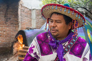 A close-up of a man from the Huichol tribe in Mexico and a temazcal in the background