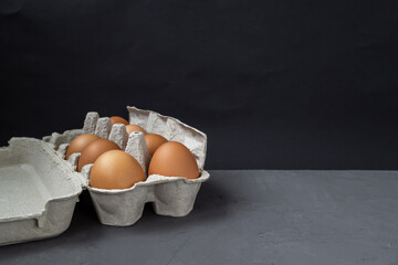 Egg carton. A full tray of brown eggs on a dark background in a standard package