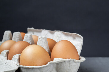 Egg carton. A full tray of brown eggs on a dark background in a standard package