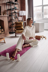 Pretty young calm female meditating relaxing sitting on natural mat in cozy home interior on weekend. Woman's wellness