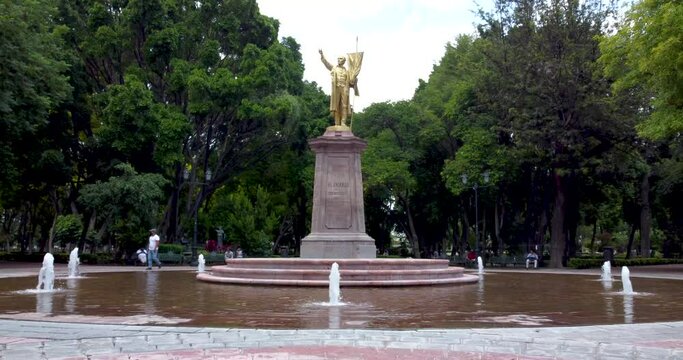 Statue of miguel hidalgo in the central park of Queretaro, Mexico , people walking in Alameda Hidalgo.