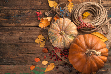 Festive autumn background of pumpkins, berries and foliage on a brown wooden background.