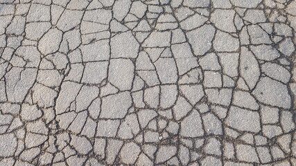 Top view of an old asphalt road in wet cracks