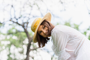 Brunette woman in sun hat looking away in summer park