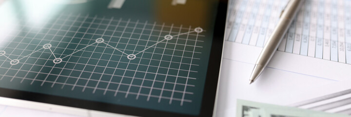 American banknotes, along with financial statement and graph with business figures, lie on table
