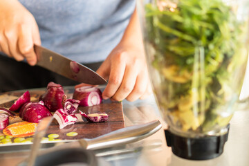 Brown hands chopping purple onions for a Venezuelan guasacaca sauce