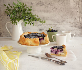 Wild  blueberry pie with two mugs of tea and a bucket of blueberries and cutting piece lay nearly. jug with blueberry sprigs. Place for text   