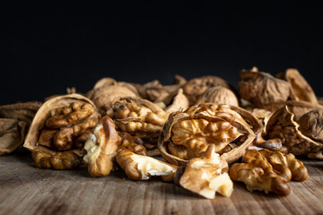 Whole walnut and walnut kernels on a rustic table with a black background