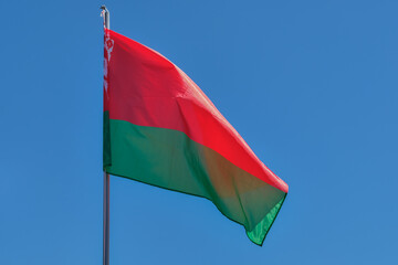 the flag of the republic of belarus develops against a blue sky