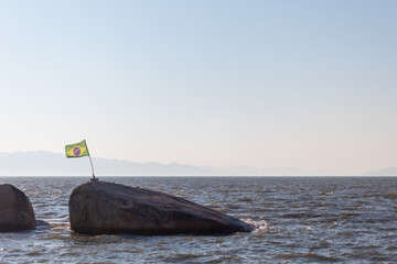 Naklejka premium Brazilian flag flying on top of a rock in Florianópolis