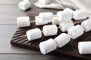 Sticks with marshmallows on wooden table, closeup