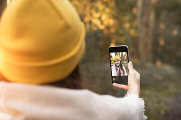 young woman wearing a yellow cap, in the forest taking a selfie