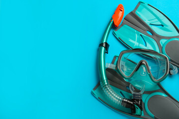 Pair of turquoise flippers and mask on light blue background, flat lay. Space for text © New Africa