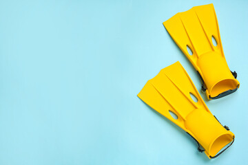 Pair of yellow flippers on light blue background, flat lay. Space for text © New Africa