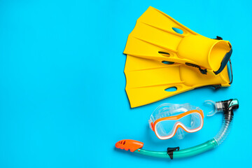 Pair of yellow flippers and mask on light blue background, flat lay. Space for text