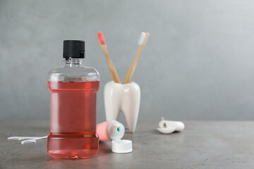 Mouthwash and other oral hygiene products on grey table, space for text