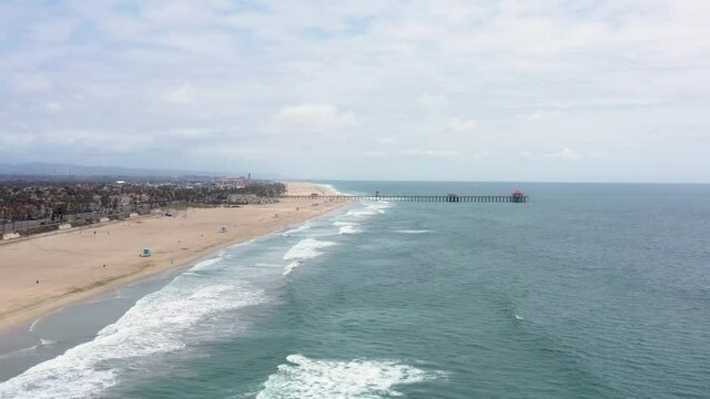 Aerial drone view of Huntington Beach Pier coastline with Pacific Ocean waves rolling along beach_03