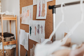 Snapshot of drawn new dress designs on wall. Photo of paper sheets with painted colored stylish garments