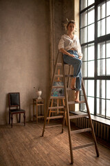 Artist female sitting on the ladder and looking in the window