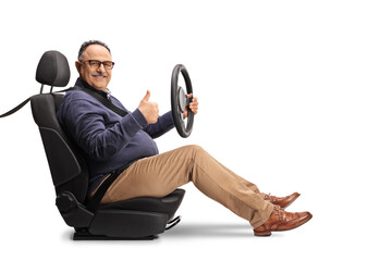 Cheerful mature man sitting in a car seat, holding a steering wheel and showing thumbs up
