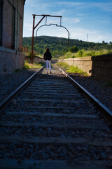 mujer con pantalón blanco paseando por las vías del tren