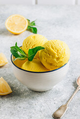 Scoops of lemon ice cream in a bowl on rustic table.