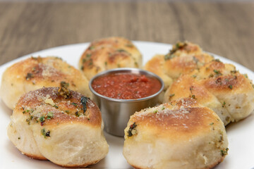 Side dish appetizer of garlic flavored bread rolls on a plate served with marinara dipping sauce