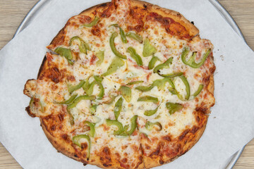 Overhead view of health conscious pizza with melted cheese and chopped bell peppers and a special...