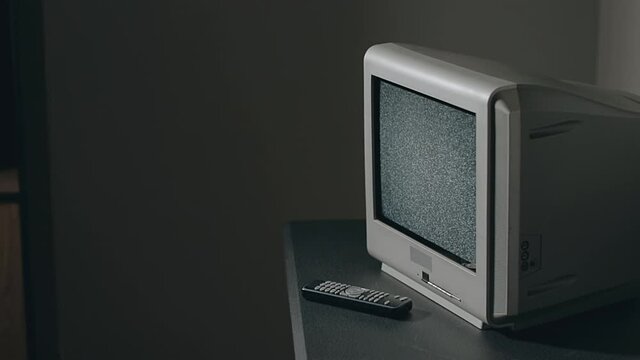 Broken Television - Old Silver TV on Black Table in Dark Room. Search for Signal. Distortion on the Screen. Close-Up, Dinamic Shot, Film Grain