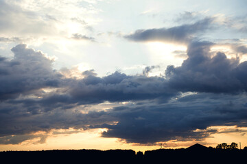 Colorful sunset with clouds in summer over the silhouette of the village. Twilight bright sky