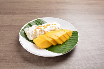 Thai fresh mango fruit with glutinous sticky rice in sweet coconut cream sauce on wood background asian dessert menu