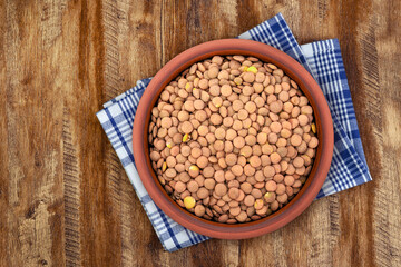 Walnut wood textureLentils in a Ceramic Bowl. These nutritious legumes are high in protein and fiber. The image is a cut out, isolated on a white background, with a clipping path.