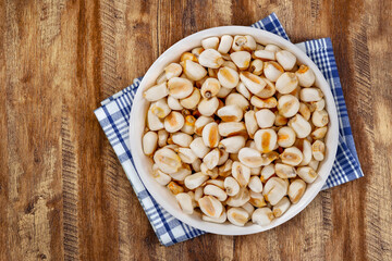 Top view of bowl with white corn for cooking on wooden table background