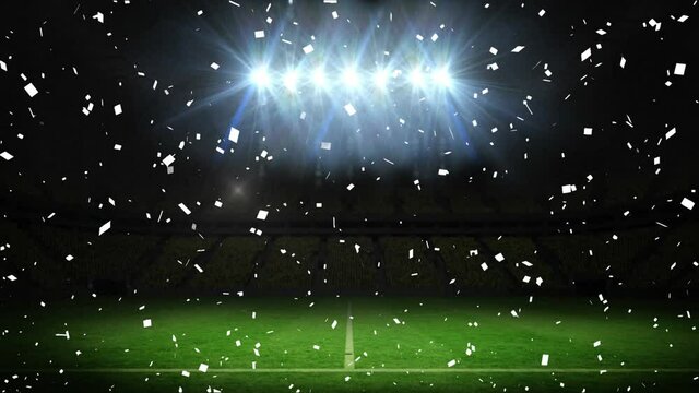 Animation of white confetti falling over floodlit pitch at sports stadium at night