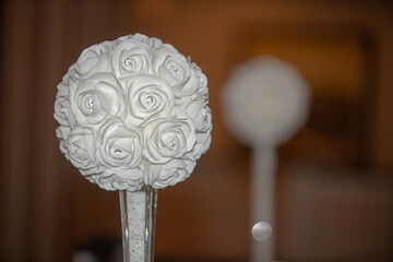 White round faux flower in glass cylinder vase centerpiece at wedding reception table setting