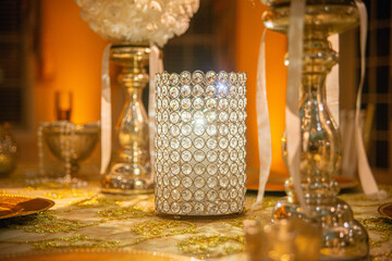 Crystal studded cylinder candle holder centerpiece at wedding reception table with warm lighting