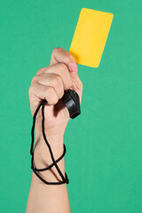 referees hand holding a yellow card and whistle
