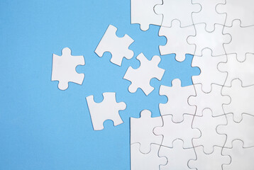 Unfinished white jigsaw puzzle pieces on blue background - obrazy, fototapety, plakaty